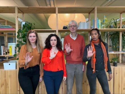 Vier medewerkers van Tûmba doen het gebaar 'Stop!' met hun hand, om te laten zien dat ze geweld tegen vrouwen willen stoppen.