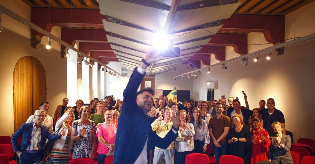 De spreker maakt een selfie met het publiek tijdens het regenboogsymposium.