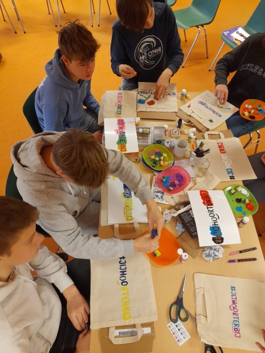 Een groep leerlingen maakt een herinnering met de #jijhoorterbij tijdens een creatieve workshop van Tûmba.