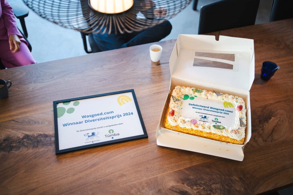 Taart en een fotolijst met tekst 'Wasgoed.com winnaar diversiteitsprijs 2024'