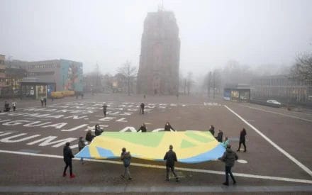 Groep mensen die de Mensenrechtenvlag met z'n allen laten wapperen bij de Oldehove in Leeuwarden