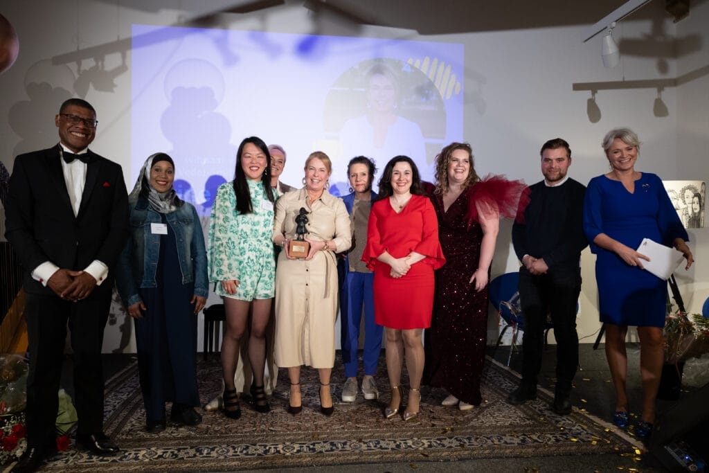 Groepsfoto met de winnaar, nummer twee, drie, de juryvoorzitter, de gedeputeerde van Provincie Fryslân, directeur van Tûmba en de sprekers tijdens de Els Veder-Smit prijs op 8 maart 2025 Internationale Vrouwendag